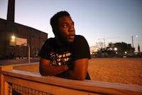 a man leaning against a fence at dusk