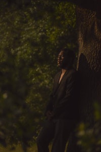 a man leaning against a tree